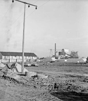 Wohnungsbau: hinten links Wohnblock im Rohbau: vorn rechts Strommast: hinten links Hartsteinwerk "Glückauf": im Vordergrund Baugelände mit Sandhaufen: darauf zwei Pkws
