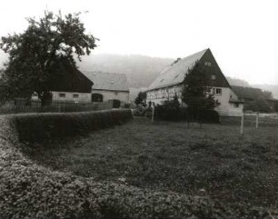 Lichtenberg, Trassenweg 28. Gehöft. Straßenansicht mit Heckeneinfriedung. Blick über eine Weide