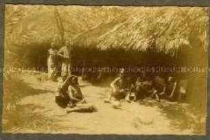 Afrikanische Männer und Frauen bei einer offenen Hütte