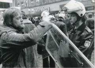 Demonstrant versucht mit einem jungen Polizisten zu diskutieren (Altersgruppe 14-17)