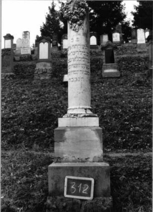 Grabstein 312 (Index: 100090410) Material: weiß. Marmor, Sockel-Sandstein Zustand: Sock. verwitt/gebroch/Textverl. Maße HxBxT: 200x45x45 cm Beschreibung: abgebrochene Säule, getreppter Sockel Symbolik: Blumenkranz um Säule Besonderheit: hebräische Buchstaben erhaben: Grabstein 312
