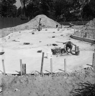 Freibad: Reeshoop: neues Planschbecken in Bau: Arbeiter beim Verstreichen des Betonbodens: Erdhaufen, Schubkarre: hinten Bauzaun