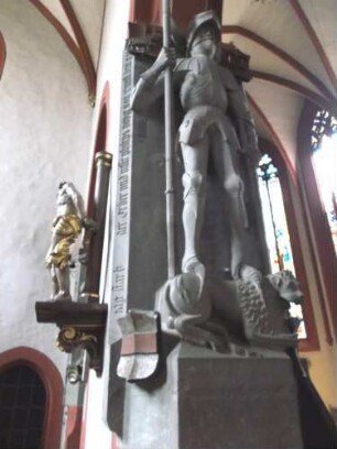 Stadtkirche-Langhaus Innen - Rienecker Kapelle - Epitaph der Voite von Rieneck (um 1500) mit vollplastischer Steinmetzarbeit in Harnisch auf Löwen sowie Umschrift und Wappen (Widder-Äxte-roter Balken)