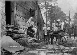 Klöpplerinnen beim Hacher-Sachs-Haus : Steinbach. Klöppelnde Frauen vor einem Blockhaus (Hacher-Sachs-Haus)