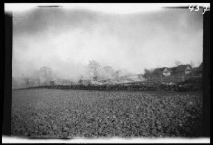Schaulen (Šiauliai, Litauen): Rauchschwaden hinter einer steinernen Ortsbefestigung ("Das brennende Schaulen nach dem Gefecht 30.4.1915")