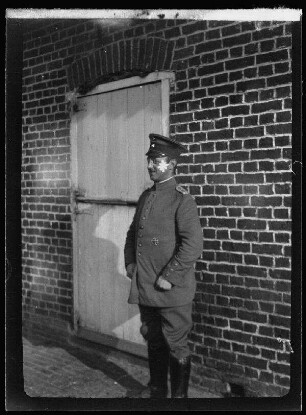 Oberleutnant Knorr vor einem Haus von der Seite