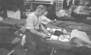 Selbstversenkung des Hochseepassagierdampfers "Columbus" am 19. Dezember 1939, Besatzungsangehörige im Internierungslager auf Ellis Island, im Schlafsaal auf dem Bett Papiere sortierend