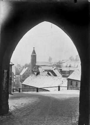 Stadtteilansicht mit Storchennest. Blick aus einem Torbogen