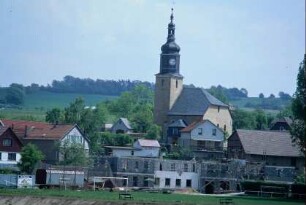 Kirche, davor Teil des Sportplatzes; ein Neubau