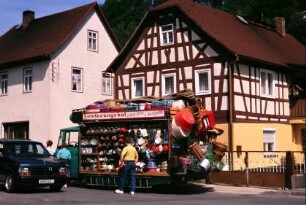 LKW mit "Sonderangeboten" steht im Dorf, angeboten werden bunte Plastikwannen, Töpfe und anderes