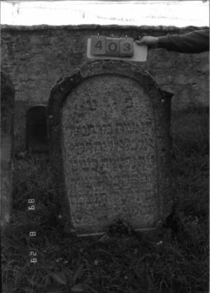 Grabstein 403 (Index: 100107898) Material: Kalkstein Zustand: verwittert Maße HxBxT: 117x73x21 cm Beschreibung: Stele mit Rundbogenabschluß, Schriftfeld eingetieft: Grabstein 403
