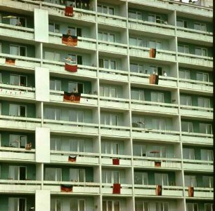 Neubau mit Fahnen geschmückt : Neubau-Plattenbau mit DDR Fahnen geschmückt, die an den Balkonen der Bewohner hängen. Einige der Bewohner stehen auf den Balkonen. Vermutlich zum 1. Mai