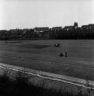Kurpark-Stadion: Am Kurpark: Neubau: Anlegen der Rasenfläche: in der Mitte Mann mit Walze, dahinter Männer mit Motorrasenmäher: hinten links Männer mit Harken: dahinter Wohnblocks am Meisenweg zwischen Bäumen