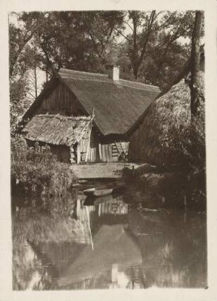 Mark Brandenburg. Leipe. Ansicht eines typischen wendischen (sorbischen) Bauernhofes in Blockbauweise und mit Reetdach. Dafur ein Heuschober. Am Bootsanleger liegt ein Spreewaldkahn im Wasser