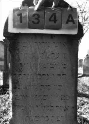 Grabstein 134 (Index: 100116060) Material: Sandstein Zustand: zum Teil stark verwittert mit Textverlust Maße HxBxT: 150x38x22 cm Beschreibung: doppelt aufgesockelte Stele mit Rundbogenabschluß, Schriftfeld auf Stele und unterem Sockel, Sockel- Schriftfeld eingetieft mit Rundbogenabschluß: Grabstein 134A