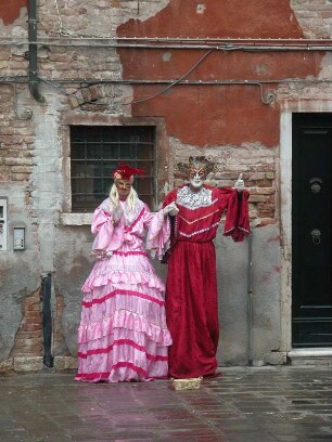 Vor einem desolaten Haus posieren diese beiden Straßenkünstlerin Venedig in historischem Kostüm