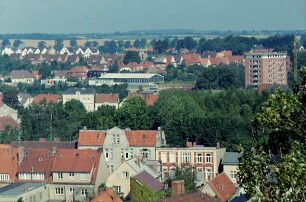 Blick vom Dach des Kaufhauses Nickel Richtung Nordosten auf Wohn- und Geschäftshäuser an Lübecker Straße und Pferdemarkt: hinten rechts Wohnblock am Berliner Ring: hinten links und Mitte Shell-Tankstelle und Mecedes-Benz-Autohandel an Segeberger Straße: dahinter Wohnhäuser am Wendum und Am Stadion: im Hintergrund Wiesen