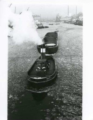 Hamburg. Hafen. Winter. Ein mit Kohle beladener Schleppverband fährt im teilweise zugefrorenen Hafenbecken zum Kraftwerk