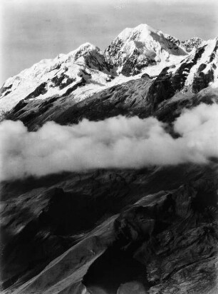 Der Illampú : Blick auf den Berg Illampú in Bolivien. Die Bergspitze ist von Eis, Schnee und Gletschern bedeckt. Auf halber Höhe eine Nebelbank.