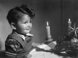 Kinderbilder. Kleiner Junge vor einem Adventskranz