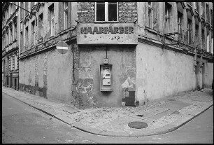 Hausfassade an einer Straßenecke mit Inschrift "Haarfärber" und Telefon