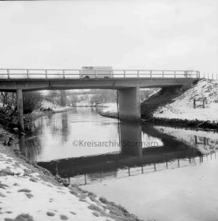 Trave: vorn links Böschung: hinten Brücke: darauf Lieferwagen: hinten Knicklandschaft: Winter