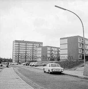 Schanzenbarg: vorn Fußweg und Straße: hinten links Personengruppe: vorn und hinten Mitte parkende Autos: hinten links mehrgeschossiges Hochhaus; hinten rechts zwei viergeschossige Wohnblocks ind Straßenlampe: 20. Juni 1968