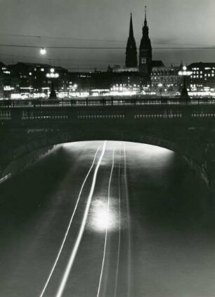 Hamburg bei Nacht. Langzeitbelichtung. Lichtspuren eines Alsterdampfers, der die Lombardsbrücke durchfährt