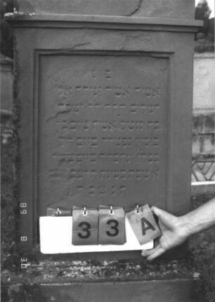 Grabstein 33 (Index: 99609669) Material: Sandstein Zustand: stark verwittert, versalzen Maße HxBxT: 189x65x30 cm Beschreibung: Stele, Giebelabschluß mit Verdachung, Mittelpalmette, Schriftfeld rechteckig eingetieft, getreppter Sockel, unten Rusticaimitat: Grabstein 33A