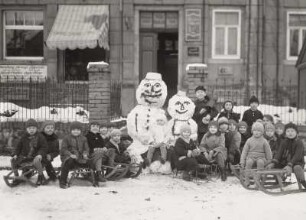 Kindergruppe mit Schlitten und Schneemännern vor dem Fotogeschäft Hanisch