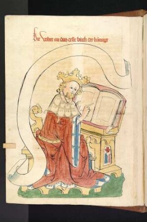 König am Pult deutet auf ein Buch