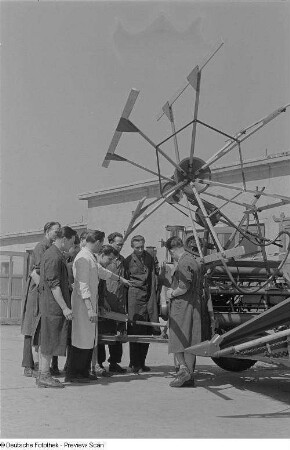 Angehörige der Fachschule für Landwirtschaftsmaschinenbau beim Unterricht vor einem Mähdrescher