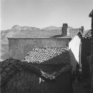 Dorfansicht : Blick durch die Gassen At Hicems. Im Hintergrund sind die umliegenden Berge zu erkennen.