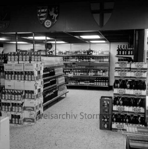 Käselau: Kaufhaus: Bahnhofstraße: vor Eröffnung am 23. November 1972: Innenansicht: Getränke-Abteilung: Regale mit Spirituosen, rechts Getränke-Kästen