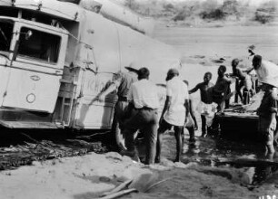 Nach der Flussüberquerung : Expeditionsteilnehmer und andere Personen schieben das Expeditionsfahrzeug an Land
