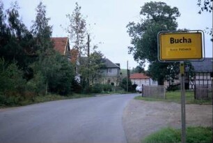 Ortseingangsschild, Straße und Gebäude