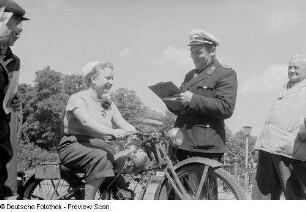Polizist im Gespräch mit einer Frau (auf dem Motorrad sitzend)