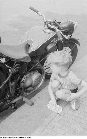 Kleiner Junge, an einem Motorrad spielend