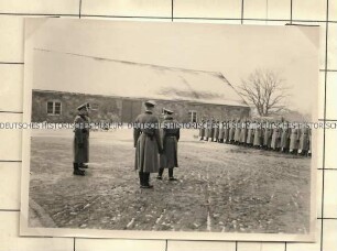 Angehörige der Ordnungspolizei in Aufstellung auf einem Innenhof vor einem Stallgebäude