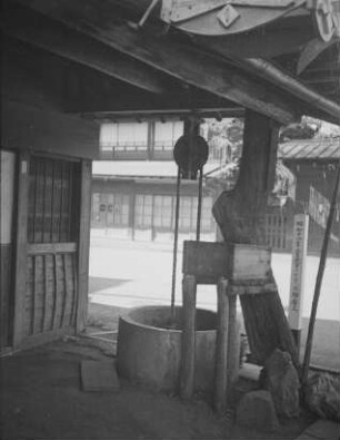 Brunnen in Fuchū (Tokio) : Überdachter Ziehbrunnen neben einem Gebäude