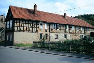 sehr langgezogenes Wohnstallhaus (?), daneben großer Garten mit Staketenzaun