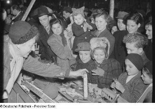Kinder an einem Stand mit Holzspielzeug auf dem Weihnachtsmarkt