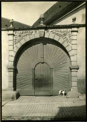 Tanzstr. 58. Tor, in den Zwickeln Laubwerk, auf dem Gesims Zapfen und zwei Kugeln