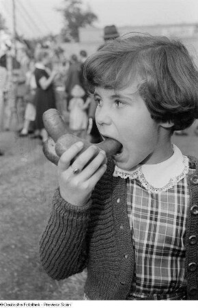 Mädchen mit Bockwurst im Brötchen auf der Kleinmesse am Cottaweg