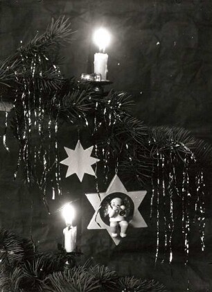 Weihnachtsbaumzweig mit Kerzen, hölzernem Stern und Bläser-Engel auf einem Stern (vor 1930; Wendt und Kühn)
