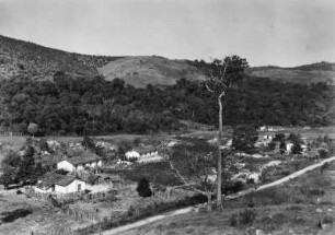 Landschaft mit Fazenda : Eine Fazenda und eine Straße in einer hügeligen Landschaft mit Baumgruppen im Hintergrund.