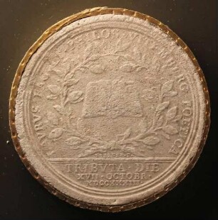 Ein aufgeschlagenes Buch zwischen zwei gekreuzten Lorbeerzweigen (Revers)