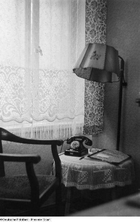 Blick in eine Zimmerecke mit einer Stehlampe und einem Telefon auf einem Beistelltisch