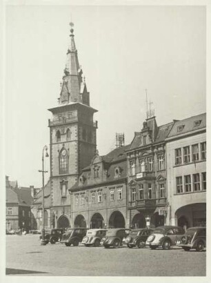 Komotau (heute Chomutov). Blick über den Marktplatz zur von 1518 bis 1539 errichteten spätgotischen Dekanalkirche Mariä Himmelfahrt. Auf dem Markzplatz sind Personenkraftwagen abgestellt.