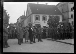 Flugzeugtaufe "Fürst Leopold von Hohenzollern" auf dem Leopoldplatz in Sigmaringen; Blick in Richtung Hofbuchhandlung Liehner; zahlreiche Uniformierte des Stahlhelm und von NS-Gliederungen, im Vordergrund mit Hut und Mantel: Regierungspräsident Carl Simons, daneben in Stahlhelm-Uniform der Kabinettchef des Fürsten von Hohenzollern, Franz Freiherr von Hallberg, daneben mit hellem Hut dessen Ehefrau; davor Fürstin Margarete von Hohenzollern, daneben in Stahlhelm-Uniform mit Hohenzollernwappen am Ärmel: Fürst Friedrich von Hohenzollern
